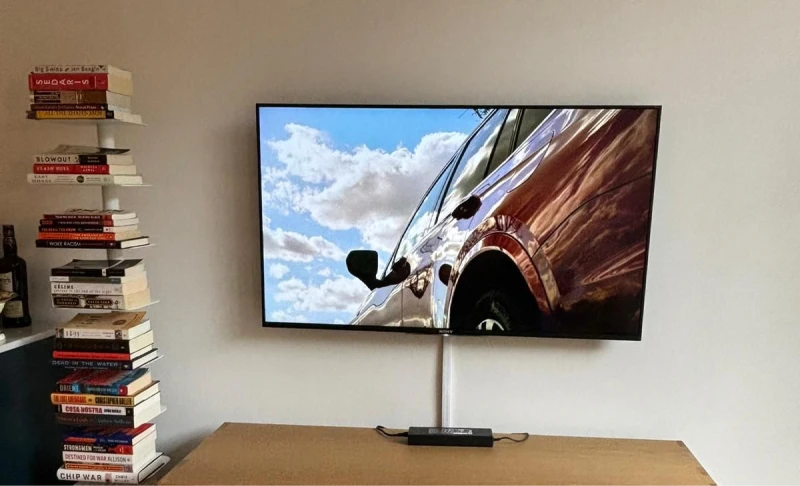 Flat-screen TV mounted on a wall above a console table with visible wire concealment