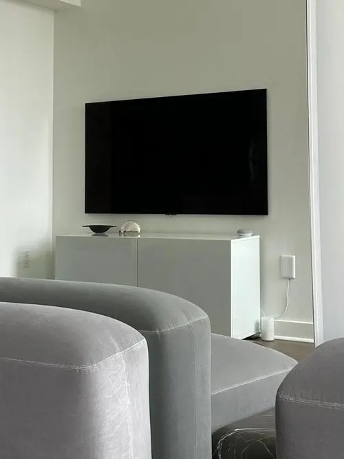 TV mounted on wall in front of grey sofa