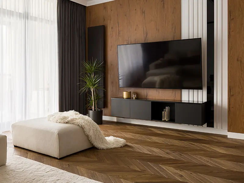 Elegant designed living room with big television screen, wooden floor and wall TV mounted on a golden frame to resemble painting