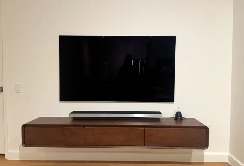 Turned off television mounted on white wall over wooden furniture