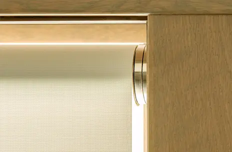 Closeup of beige roller shade installed on a window. The shade protects the interior from the sunlight during the day