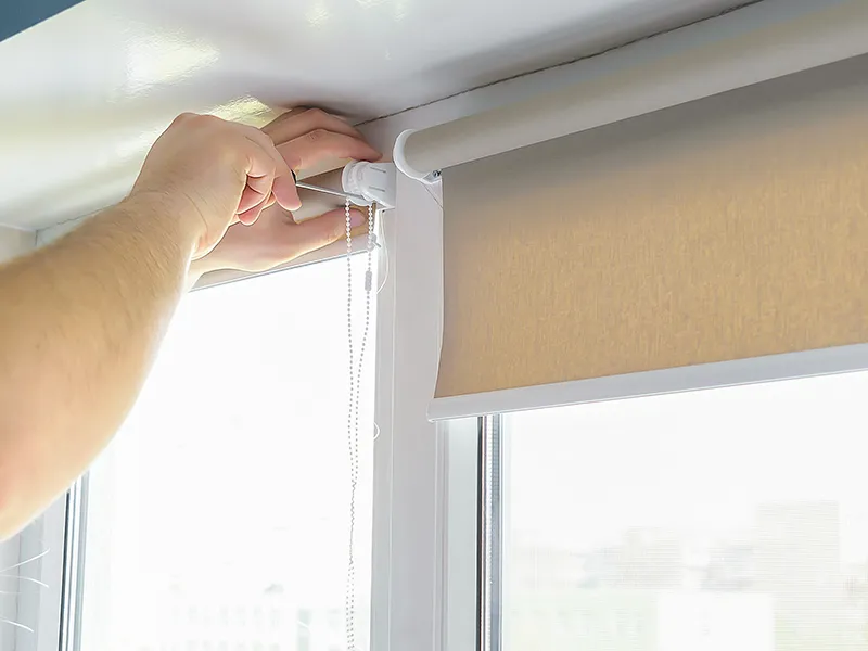 Man worker installing attached mounting bracket on roller blinds, shades on window screens renovation